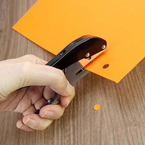 Hand using Beefy Built To Last Handheld Hole Punch 8mm Five Sixteenth Inch for cards and tags on orange paper