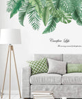 Living room with palm tree wall decals above a gray sofa, featuring green leaves; reusable stickers for decor, size 35x17 inches.