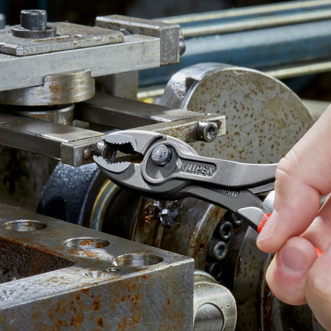 Close-up of hand using 8 Inch Pliers With Front And Side Gripping, Front Jaw Grips Stripped Screws, Side Jaw On Metal Machinery