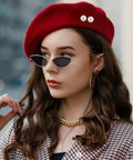 Woman wearing a red beret with pearl details and sleek sunglasses, showcasing stylish accessories.