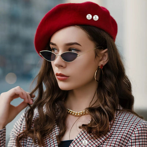 Woman wearing a red beret with pearl details and sleek sunglasses, showcasing stylish accessories.