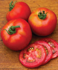 Three whole and sliced red tomatoes on a wooden surface. Early Girl Slicing Tomato Seeds For Home Garden Non GMO Indeterminate 50 Pack.