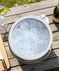 Keep It Frosty 4.8 Liter Insulated Ice Bucket With Snug Fit Lid And Drop Handle Scoop filled with ice on a wooden table.