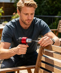 Person using Rivet Nut Adapter Kit For Cordless Drill, Quick-Change Blind Riveter Insert on wooden furniture outdoors, red tool.