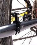 Ultra Portable Bike Wheel Truing Stand For On The Go Rim Adjustment attached to a bike frame, showing detail of clamp mechanism.