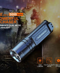 Beast Mode 5000 Lumen Flashlight With 437 Yard Throw, black aluminum design on rugged terrain, high-performance tactical use