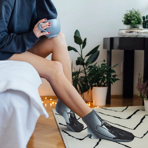 Person wearing graphic socks indoors with coffee, surrounded by plants.