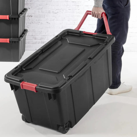 Person carrying Two Pack 160 Quart Black Stackable Rolling Storage Bins with Heavy Duty Red Latches and Smooth Glide Wheels.