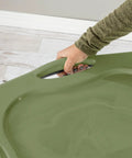 Hand gripping the handle of a Heavy Duty 17.5 Gallon Plastic Storage Bin With Clear Lid And Full Length Through Wall Handles Gray Opaque Base Stacks Tight 70 Quart Tote For Blankets And Gear.