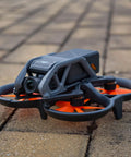 FPV drone with Avata Drone Propellers Replacement Set Orange 8 Pack, lightweight PC blades installed on outdoor pavement.