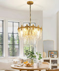 Next Level Two Layer Gold Crystal Glass Chandelier And Four Light Round Pendant Fixtures With Brushed Brass Finish hanging over a dining table.