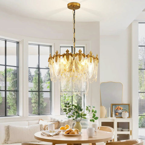 Next Level Two Layer Gold Crystal Glass Chandelier And Four Light Round Pendant Fixtures With Brushed Brass Finish hanging over a dining table.