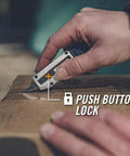 Close-up of hand using Prybrid X EDC Multitool Pocket Knife With Retractable Box Cutter Blade And Pry Bar 8 In 1 on cardboard.