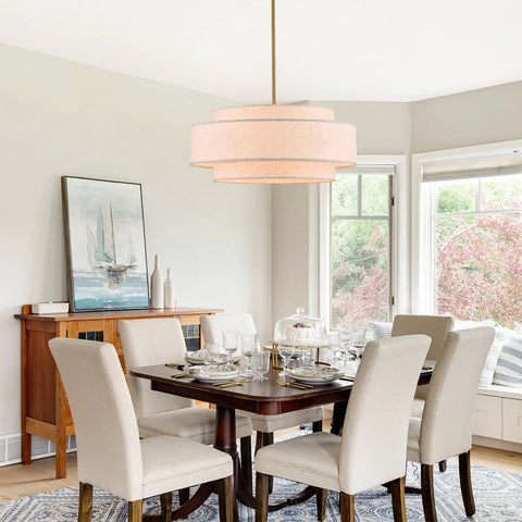 Totally Iconic 24 Inch Linen Drum Chandelier With Six Warm Lights Featuring Sleek Gold Frame And Three Tier Vintage Farmhouse Design illuminating a modern dining room.