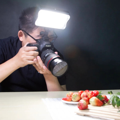 Person using Bi-Color LED Video Light 3300K-5600K With Dimmable Brightness For DSLR And Camcorder in a dark setting