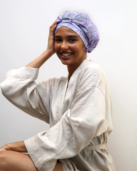 Woman wearing marble pattern reusable waterproof shower cap with nonslip silicone forehead strip, leakproof and secure fit.