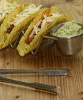 Stainless Steel 3 Grid Taco Holder with V Shaped Slots and No Spill Sauce Cups on wooden table, loaded with tacos and guacamole