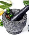 Granite mortar and pestle set with herbs, showcasing Mortar And Pestle Set Granite Spice Grinder 2 Cup Capacity With Anti Scratch Slip Base.