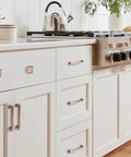 5 Inch Brushed Antique Copper Cabinet Hardware Pulls And Knobs Set installed on white kitchen cabinets.