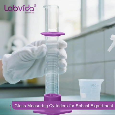 Durable Pro Grade Borosilicate Glass Measuring Cylinder Set With Hex Base And Brush Includes 10 ML 25 ML 50 ML And 100 ML Cylinders Class B Lab Glassware For Chemistry Experiments And Education. White-gloved hand holding measuring cylinder in lab.