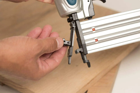 Close-up of a hand adjusting the tool-less jam clearing mechanism on the Rock Solid 18 Gauge 2 Inch Brad Nailer Kit.