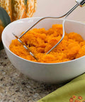 Ultimate 33-Piece Silicone And Stainless Steel Utensil Set potato masher in use over a bowl of mashed potatoes