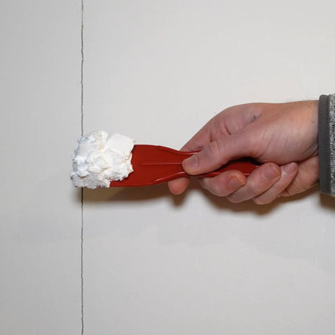 OneTime Lightweight Spackle For Wall Repair And Hole Filling being applied to drywall crack with a red putty knife