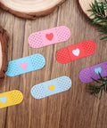 Colorful adhesive bandage-shaped die cuts with hearts on wooden surface, showcasing Happy Birthday Balloons Metal Cutting Dies For Card Making.