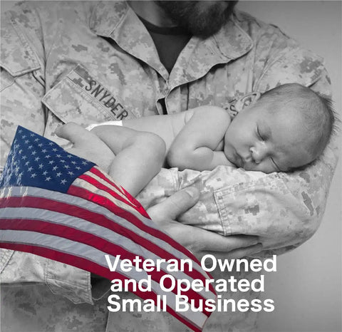 Soldier holding a sleeping baby with an American flag, representing veteran-owned and operated small business.