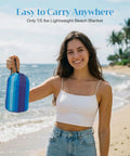 Woman holding Extra Large Beach Blanket Waterproof And Sand Free For 3 To 4 People 7 By 7 Feet Lightweight Beach Mat, packaged in a bag