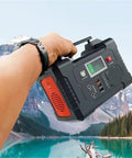 Portable AC Power Station With Fast Charging Ports, Campground Essential Backup Generator for road trips held by hand in scenic outdoor setting.