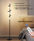 Tall Black Spiral Torchiere Floor Lamp With Remote Dimming And Color Changing LED next to a bed, remote being used