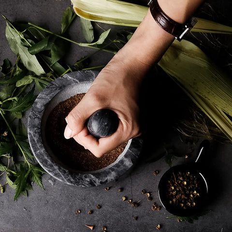 Person using Granite Mortar And Pestle Set With Gold Base For Grinding Spices Nuts And Herbs To Unlock Bold Flavor Make Fresh Guac Salsa And Pesto 2 Cup Capacity Durable Polished Surface For Easy Crushing And Consistent Texture.