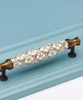 Two Pack Ceramic And Zinc Alloy Vintage Cabinet Knobs in rich brown with floral motif installed on blue cabinet, 5-inch hole spacing.