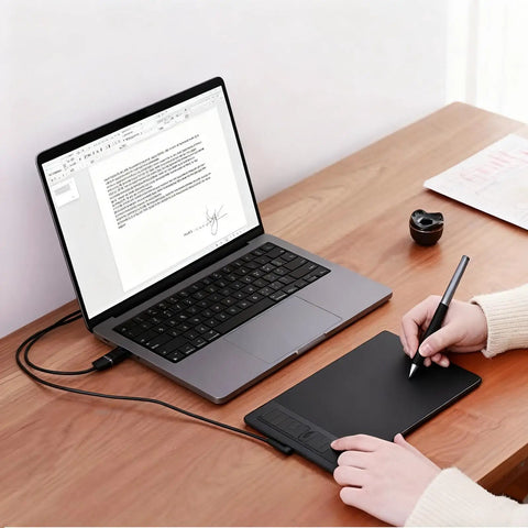 Compact Drawing Tablet With Slick Scroll Wheel And Ergonomic Stylus Delivering Sick Precision And Butter Smooth Pressure Response Perfect For Pc Artists Seeking Zero Lag Creativity And Hassle Free Setup In Sleek Black on a wooden desk next to a laptop.