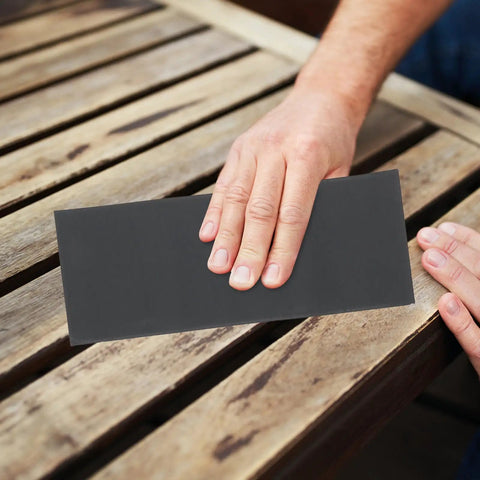 Person using Dope 45 Sheet Wet Dry Sandpaper Set Ranging 120 To 5000 Grit on wood surface for smoothing.