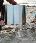 Assembly of Sturdy 19.5 Inch Fire Pit Stand For Bonfire And Other 19.5 Inch Pits Stainless Steel on a sandy surface
