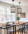 Modern 4 Light Lantern Pendant Chandelier in matte black and brass hanging over dining table in bright kitchen