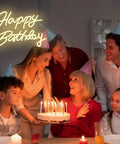 Family celebrating with a cake under lit adjustable dimmable Happy Birthday neon sign LED light up backdrop for parties.