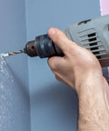 Person using a drill to create a hole in a wall for 100 Piece Heavy Duty Zinc Steel Concrete Anchors, 3/8 Inch Threaded Rod With 1/4 Inch Diameter And 1-1/2 Inch Length.