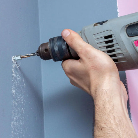 Person using a drill to create a hole in a wall for 100 Piece Heavy Duty Zinc Steel Concrete Anchors, 3/8 Inch Threaded Rod With 1/4 Inch Diameter And 1-1/2 Inch Length.