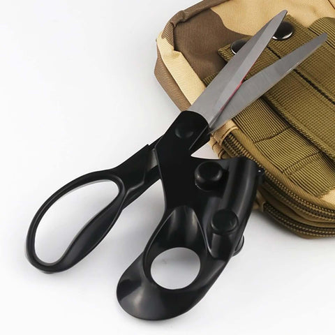 Close-up of black ergonomic sewing scissors with built-in guide beside a tan tactical backpack