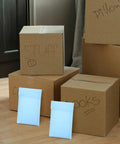 Milk Blue Bubble Mailer Bags 100 Pack Self Sealing 11x15 Plus 4 Inch with boxes labeled 'Stuff' and 'Pillows' in background