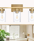 Clean Three Light Bathroom Vanity Wall Sconce In Smooth Brushed Gold Finish With Clear Retro Glass Shades over a modern bathroom mirror.