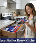 Front view of a woman in a kitchen holding BurnFIX Burn Kit first aid kit; open drawer shows blue packaging.