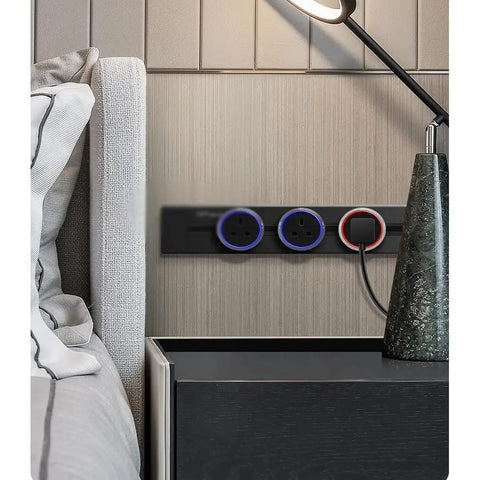 Slick Surface Mount Power Track Outlet With LED Adapter Plug And USB Charging Port For Home Kitchen Office 110 To 250 V Compatible Electrical Extension Strip No Mess Setup, mounted beside a bed.