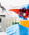 Pouring red liquid from 250ml Erlenmeyer flask with printed graduations into a small tube in a lab setting. 3 Piece Glass Erlenmeyer Flask Set 50ml 150ml 250ml with Stoppers and Cleaning Brush Borosilicate 3.3 Narrow Mouth Lab Conical Flasks with Printed Graduation for Precise Chemistry Experiments visible in background.