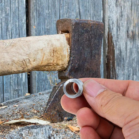 Hand holding iron wedge near axe handle, Heavy Duty Splitting Handle Metal Tapered Wedge For Axe Installation And Axe Handle Crafting.