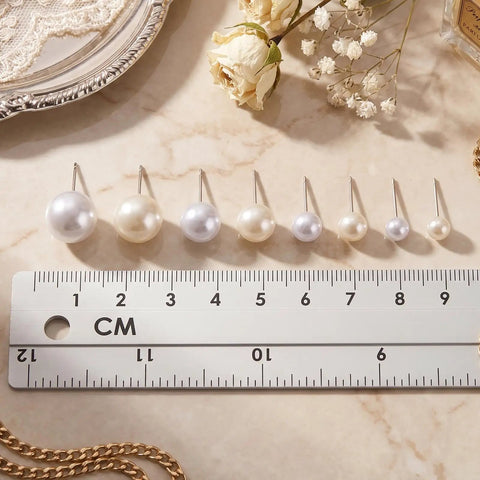 24 Pairs Pearl Stud Earrings Set For Women White And Beige Faux Pearl Studs In Four Sizes 4mm 6mm 8mm 10mm Round Ball Design Ideal For Everyday Wear Gift Idea. White and beige faux pearl studs lined up on a ruler.