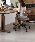 Woman sitting on office chair with 1.5 inch swivel furniture casters at wooden desk in modern room.